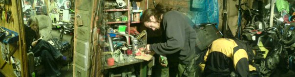 wide shot of my friend trying desperately to fix my bike in a shed-complex.