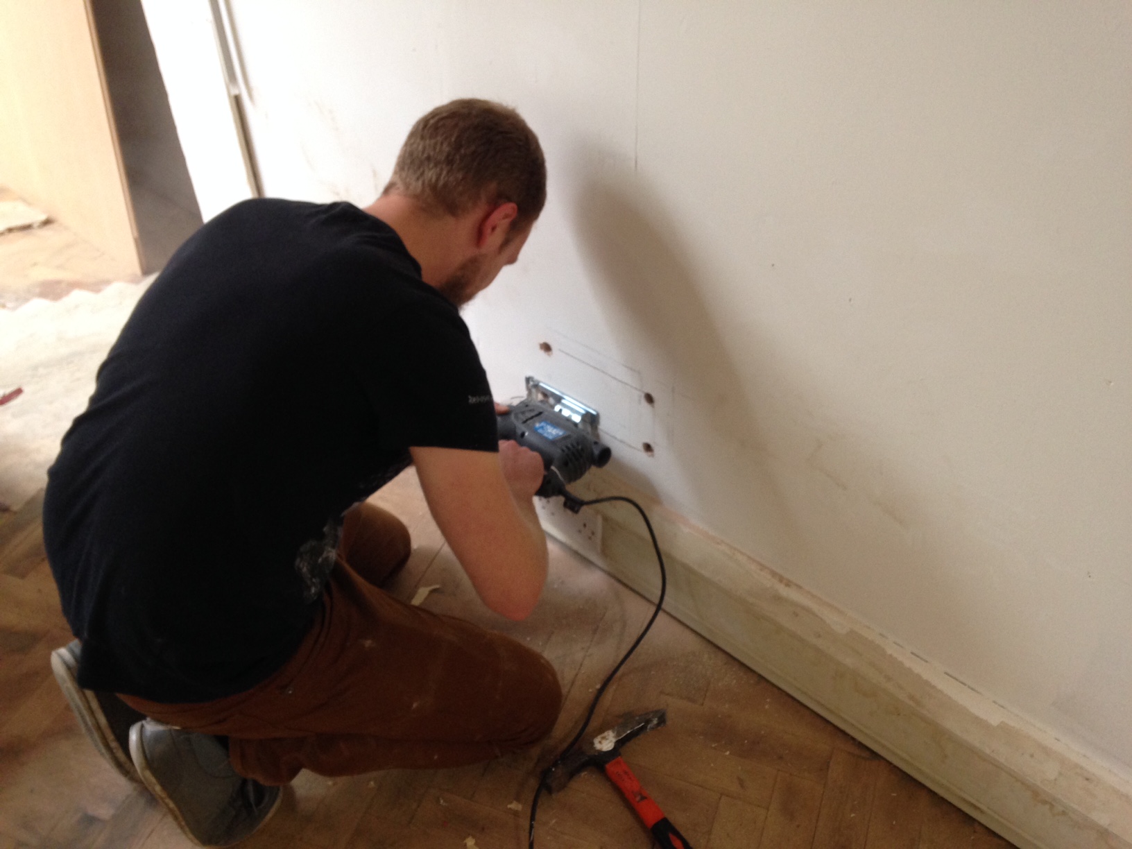 Cutting open the wall with a jigsaw to retrieve drill